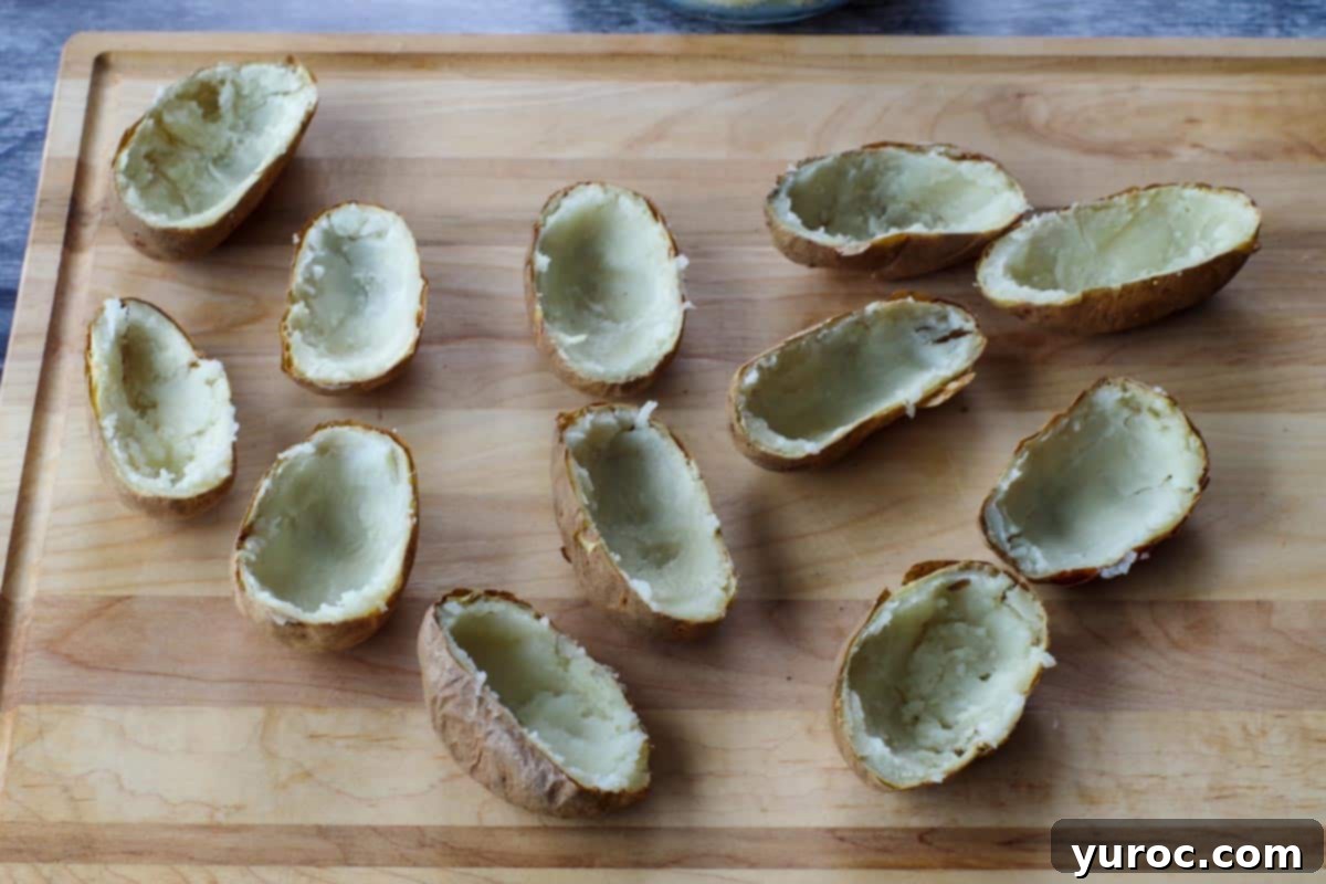 half potatoes with insides scooped out, on a wooden cutting board
