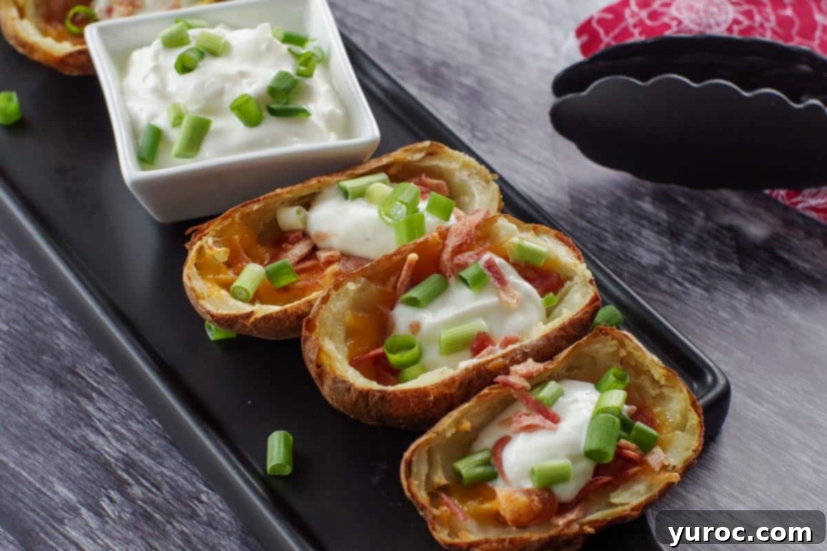 3 air fryer potato skins on a black platter with a white dish of sour cream in the middle