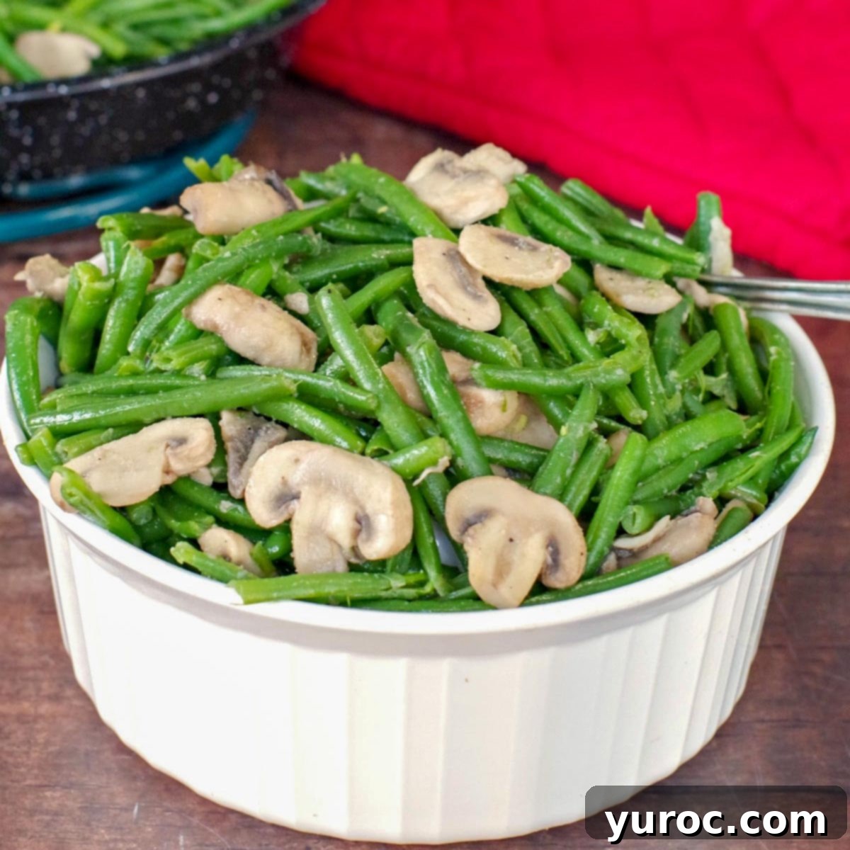 Sticky Orange Hoisin Chicken 13 Green beans and mushrooms in a white casserole dish on a brown surface, with a red oven mitt in the background
