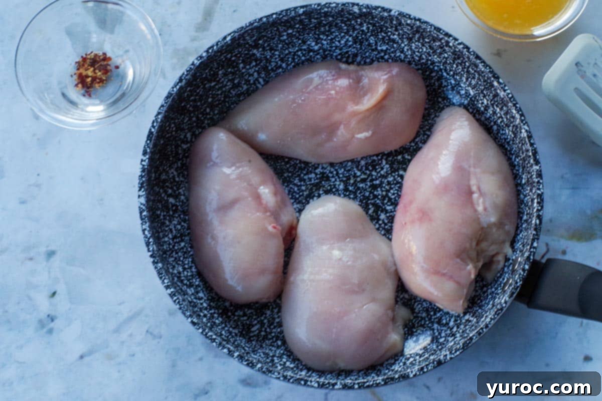 Sticky Orange Hoisin Chicken 4 Four uncooked chicken breasts browning in a hot skillet with olive oil