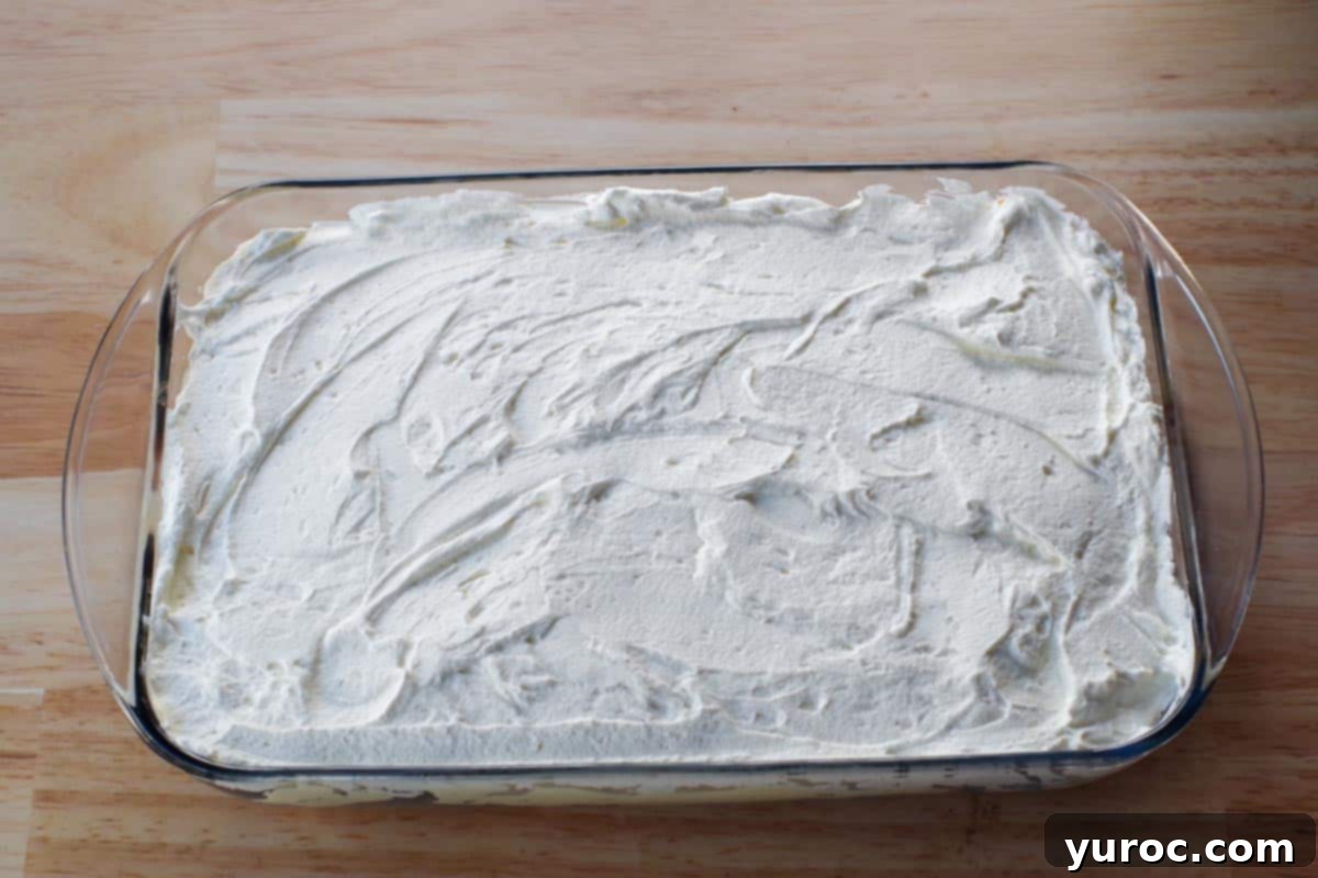 The whipped cream layer evenly spread over the pudding, creating a smooth top surface for the dessert.