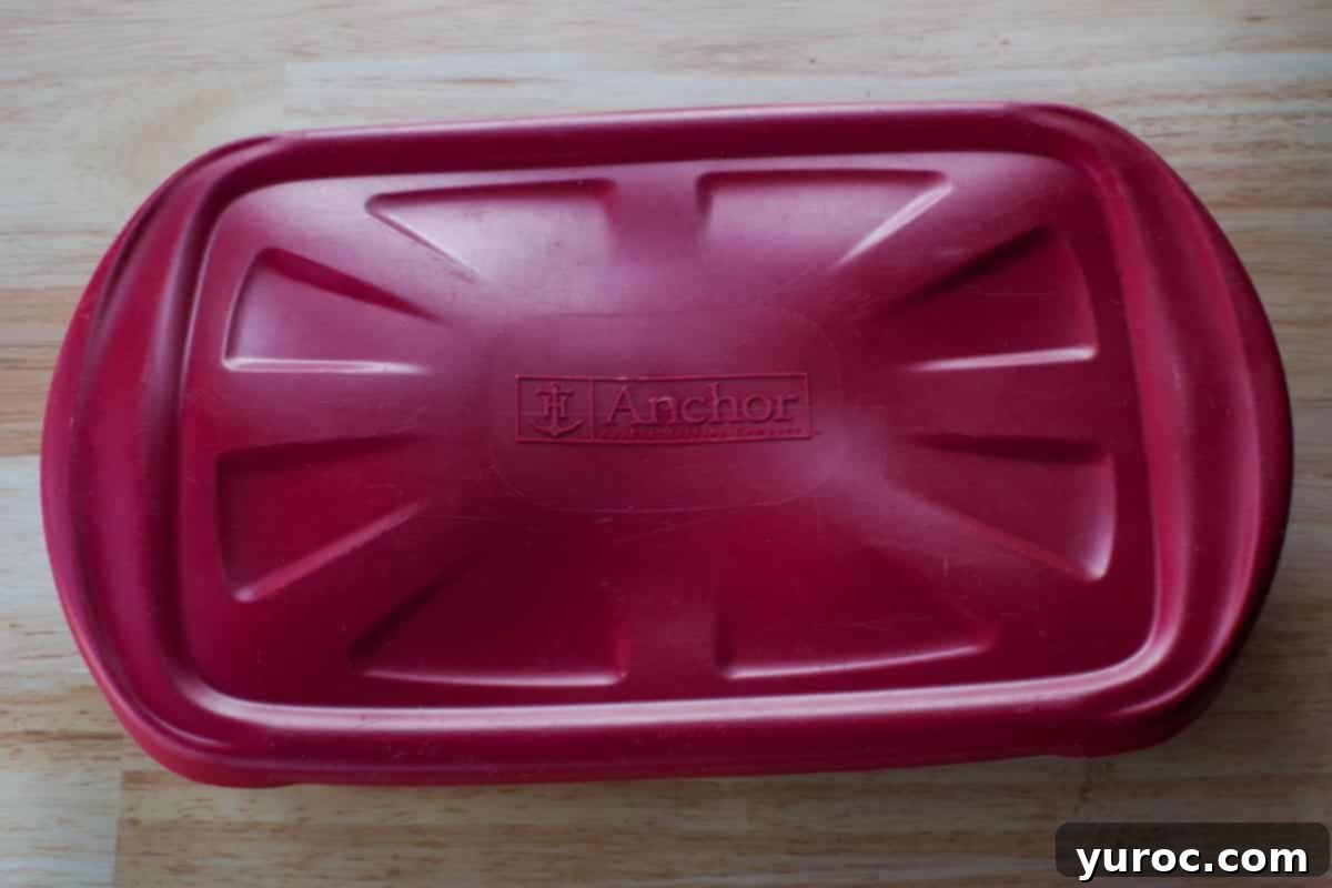 The assembled cream puff dessert in a container with a red lid, ready for refrigeration.