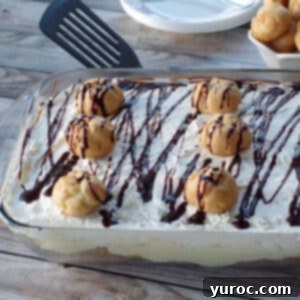 No-Bake Cream Puff Dessert, a layered cake in a glass dish, with serving plates and extra cream puffs in the background.