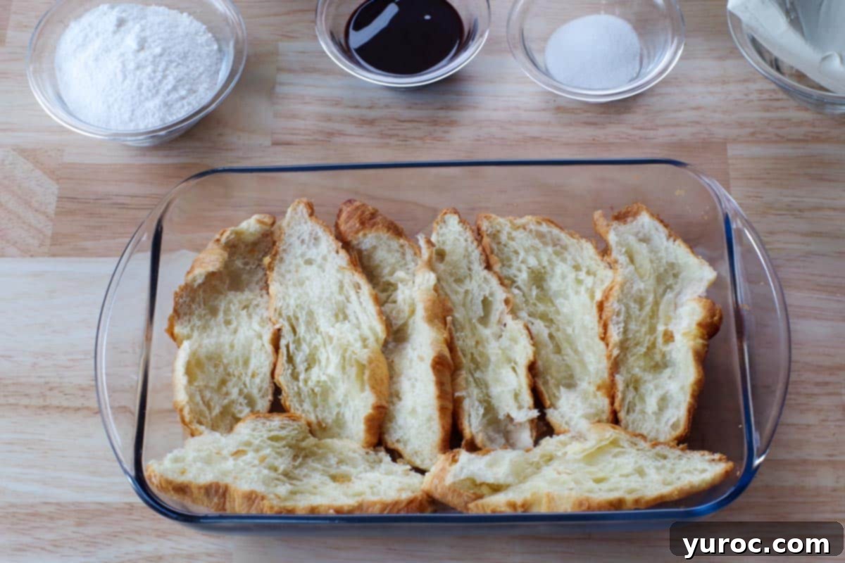 Croissants cut in half and arranged to line the bottom of a 9x13 glass baking dish, forming the dessert base.