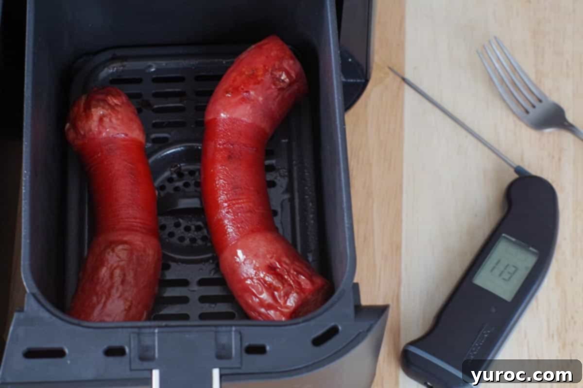 cooked kielbasa in the drawer of an air fryer with a black instant read thermometer to the right
