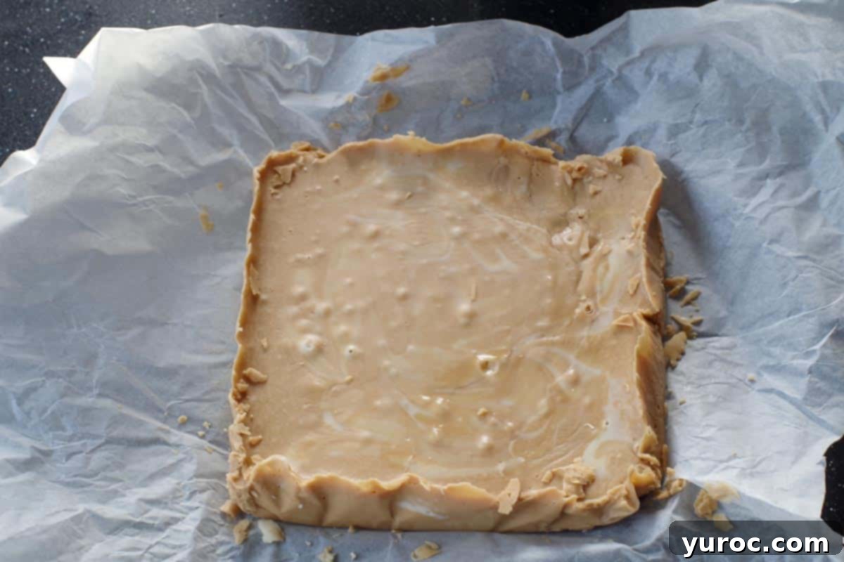 root beer fudge lifted out of pan with parchment, on cutting board