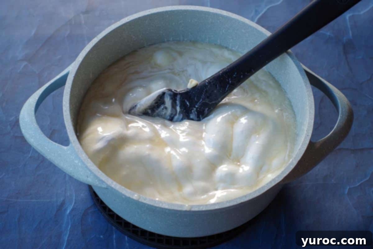 white chocolate chips and marshmallow creme added to blue pot with sugar, milk and butter mixture