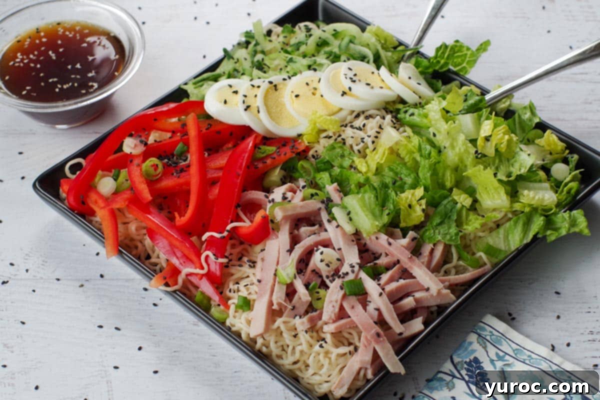 Japanese cold noodle salad on a black serving platter with a glass bowl of dressing on the side