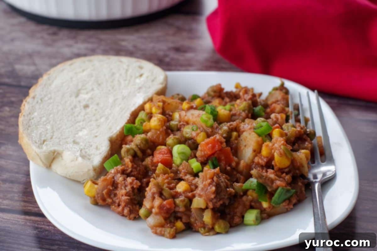 shipwreck casserole on a white plate with a fork and a piece of buttered rye bread and a casserole dish with more in the background