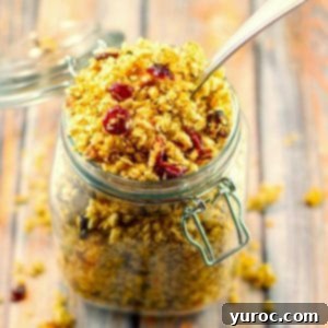 Homemade brown butter pecan granola in a glass jar with a spoon, top-down view.