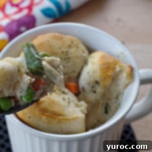 personal chicken pot pie in a white meal mug, with a bit being held up on a spoon