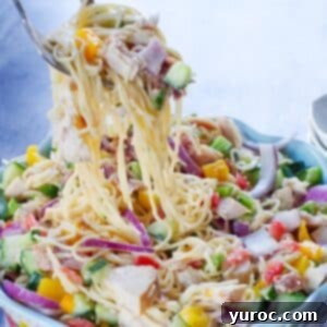 Ultimate Creamy Bacon Ranch Chicken Pasta Salad 7 chicken bacon ranch pasta salad being lifted out of a flowered bowl with salad utensils