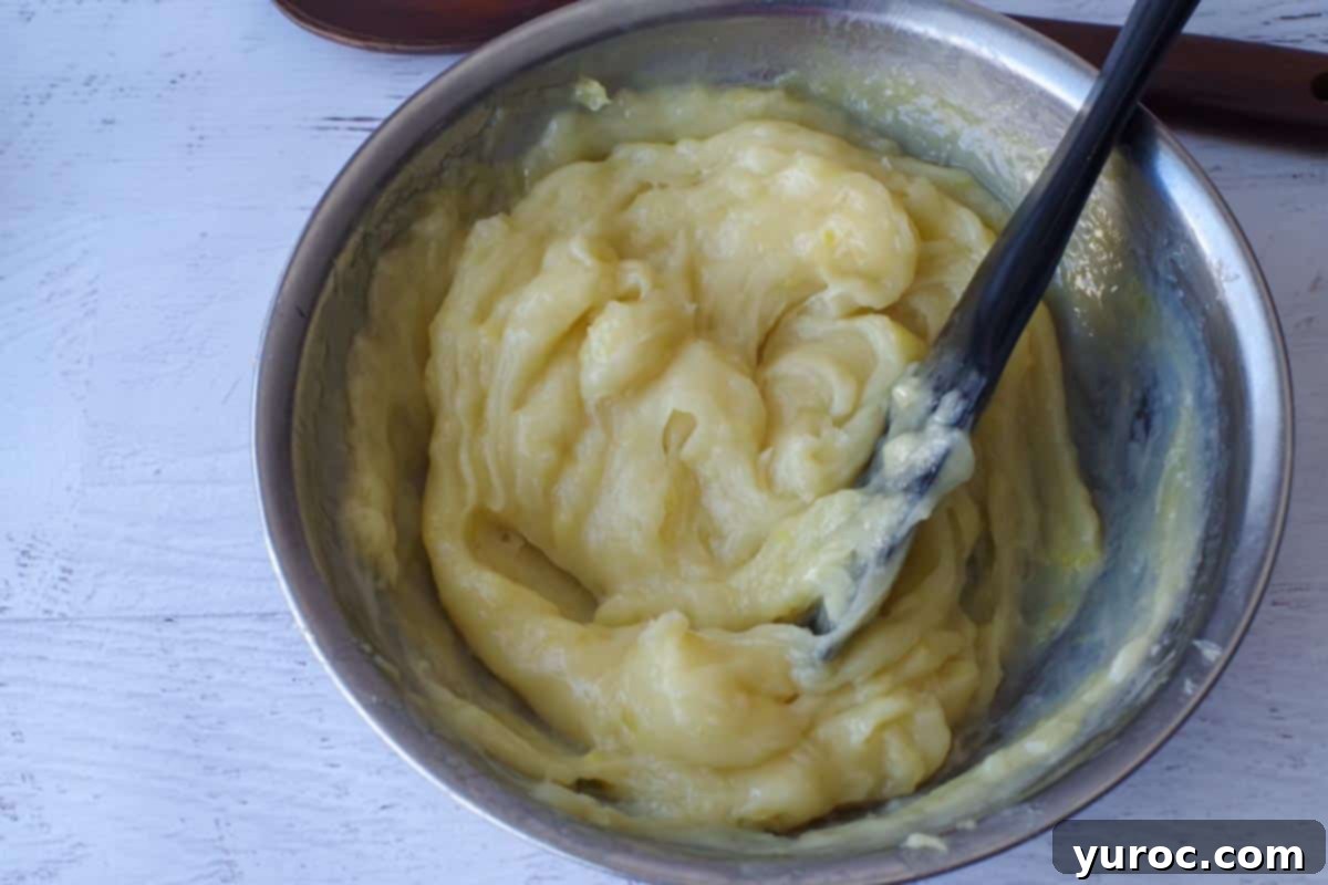 Tempered egg yolks fully incorporated into the hot lemon mixture in a double boiler top.