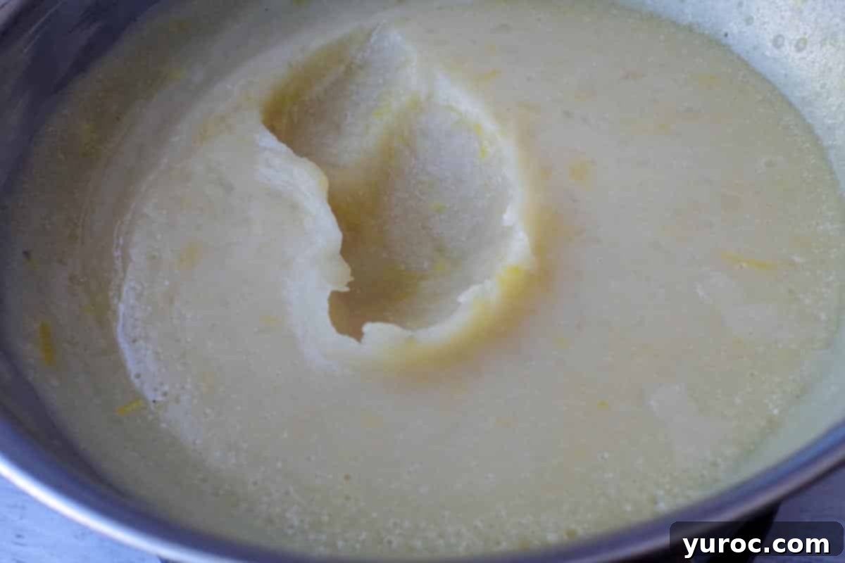 The thickened lemon filling base covered with a lid in a stainless steel bowl.