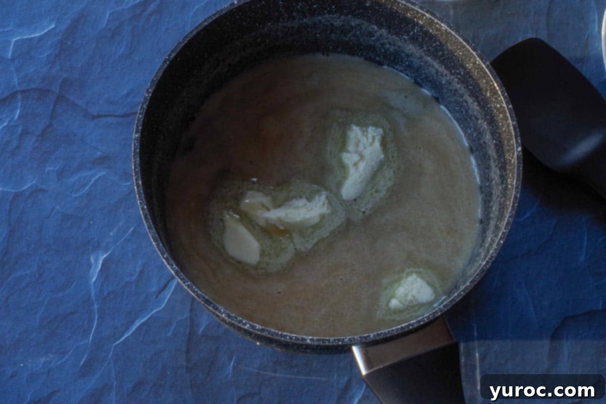 Decadent Salted Soft Butter Toffee 7 Pieces of salted butter being gradually added to the hot toffee mixture in the saucepan, enriching the flavor.
