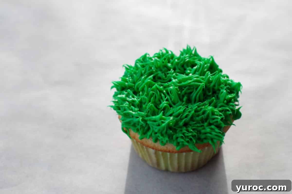 Mini Egg Hunt Cupcake Treasures 11 A cupcake fully covered in a fluffy layer of green grass frosting, ready for decorations.