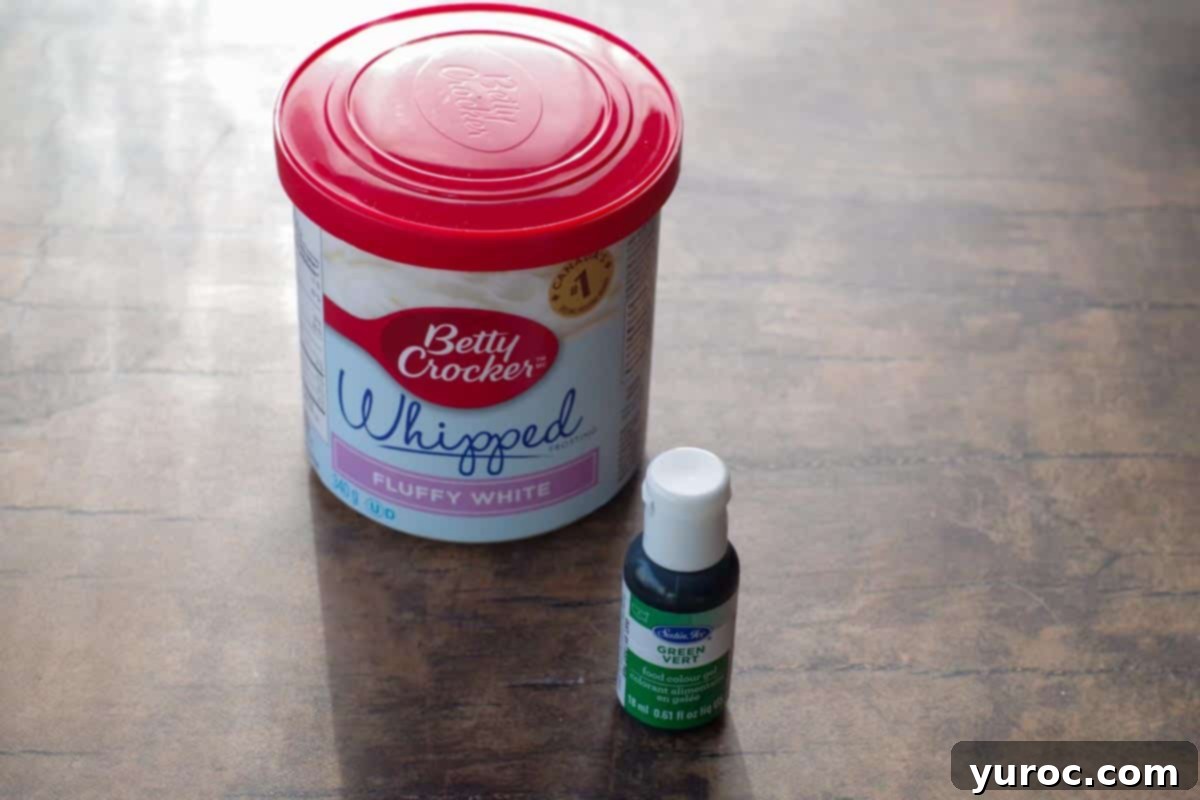 Mini Egg Hunt Cupcake Treasures 3 A container of Betty Crocker whipped fluffy white frosting positioned next to a small bottle of vibrant green gel food coloring, ready for mixing.