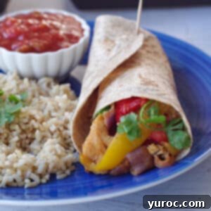 air fryer fajitas in a wrap, on a blue plate with rice, salsa and a wedge of lime