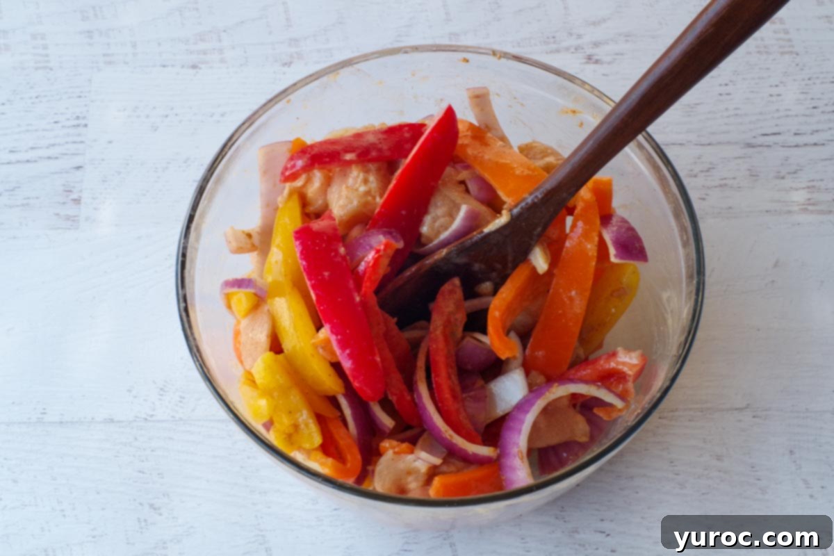 air fryer fajita ingredients in a glass bowl with a black spatula