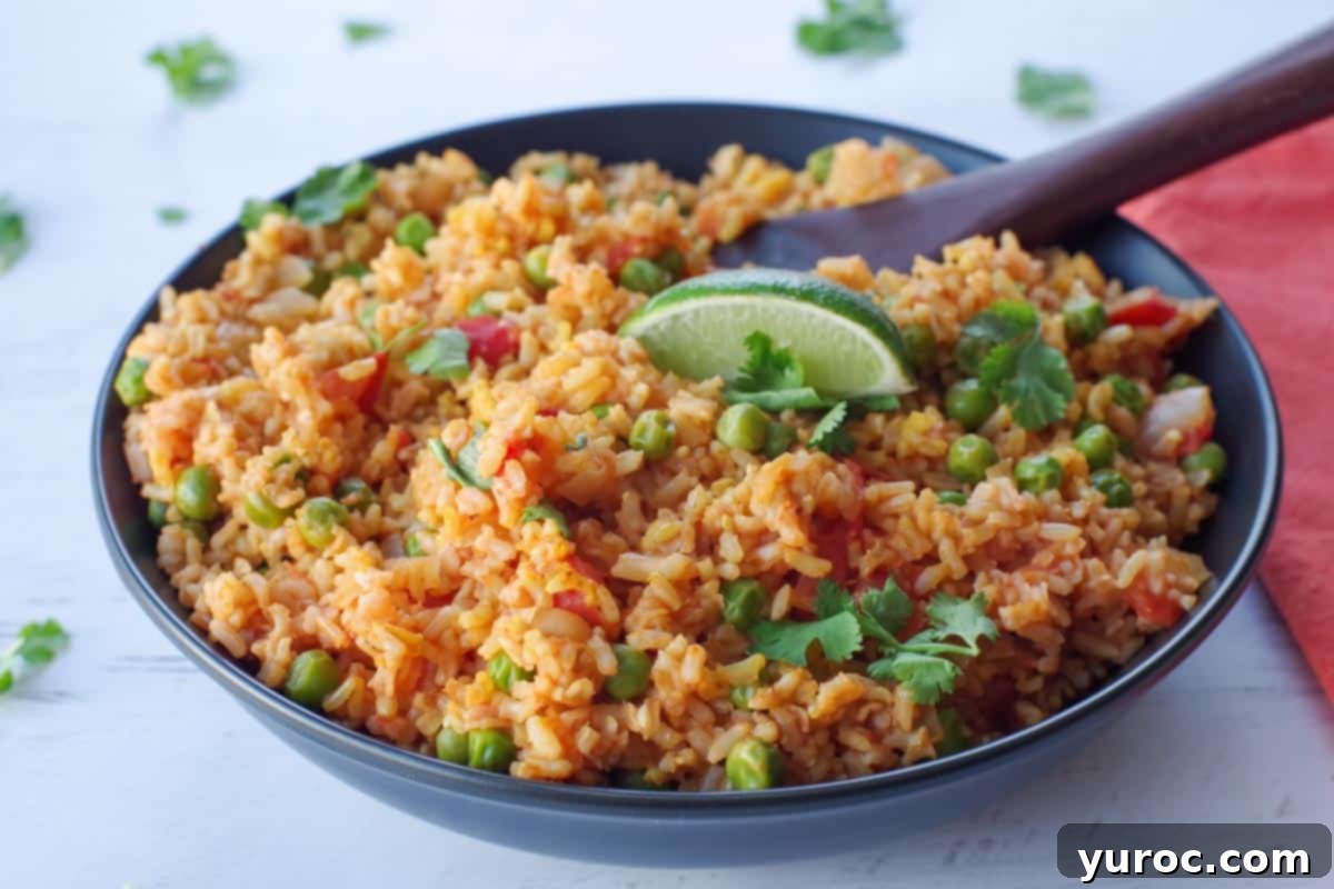 Spanish brown rice in a black bowl with a wooden spoon and sprigs of cilantro in background