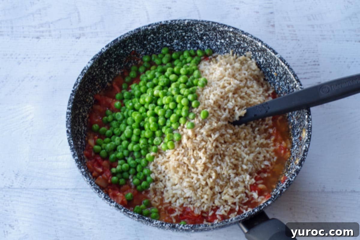 peas and rice added to tomato mixture in pan