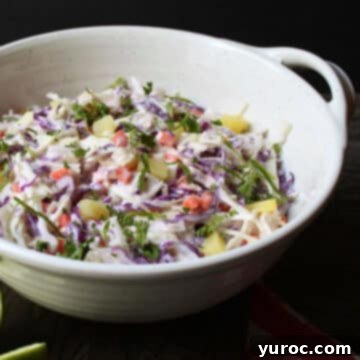 What to Serve with Carnitas: 25 Irresistible Recipes 11 Tropical Pineapple Coconut Coleslaw served in a sage green and white bowl.