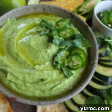 What to Serve with Carnitas: 25 Irresistible Recipes 14 Cilantro Lime Hummus in a grey bowl, surrounded by sliced vegetables.