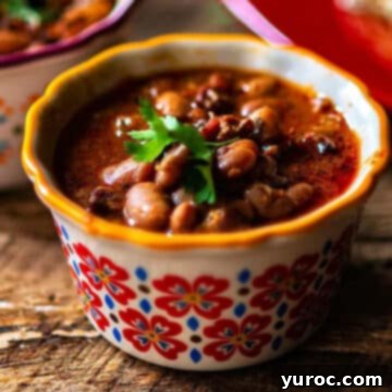 What to Serve with Carnitas: 25 Irresistible Recipes 26 Charro Beans served in a white dish with an orange rim and a floral pattern.