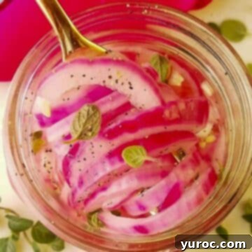 What to Serve with Carnitas: 25 Irresistible Recipes 10 A jar of bright pink pickled red onions, photographed from above with a spoon inside.