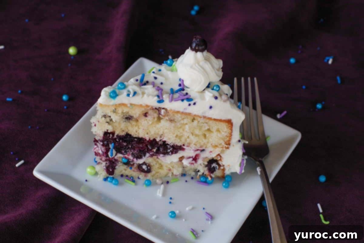 A delectable slice of Saskatoon berry cake displayed on a pristine white plate, accompanied by a fork, showcasing the beautiful layers and rich berry filling.