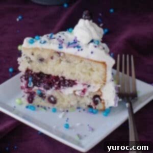 A delightful slice of Saskatoon berry cake on a white plate with a fork, ready to be enjoyed.