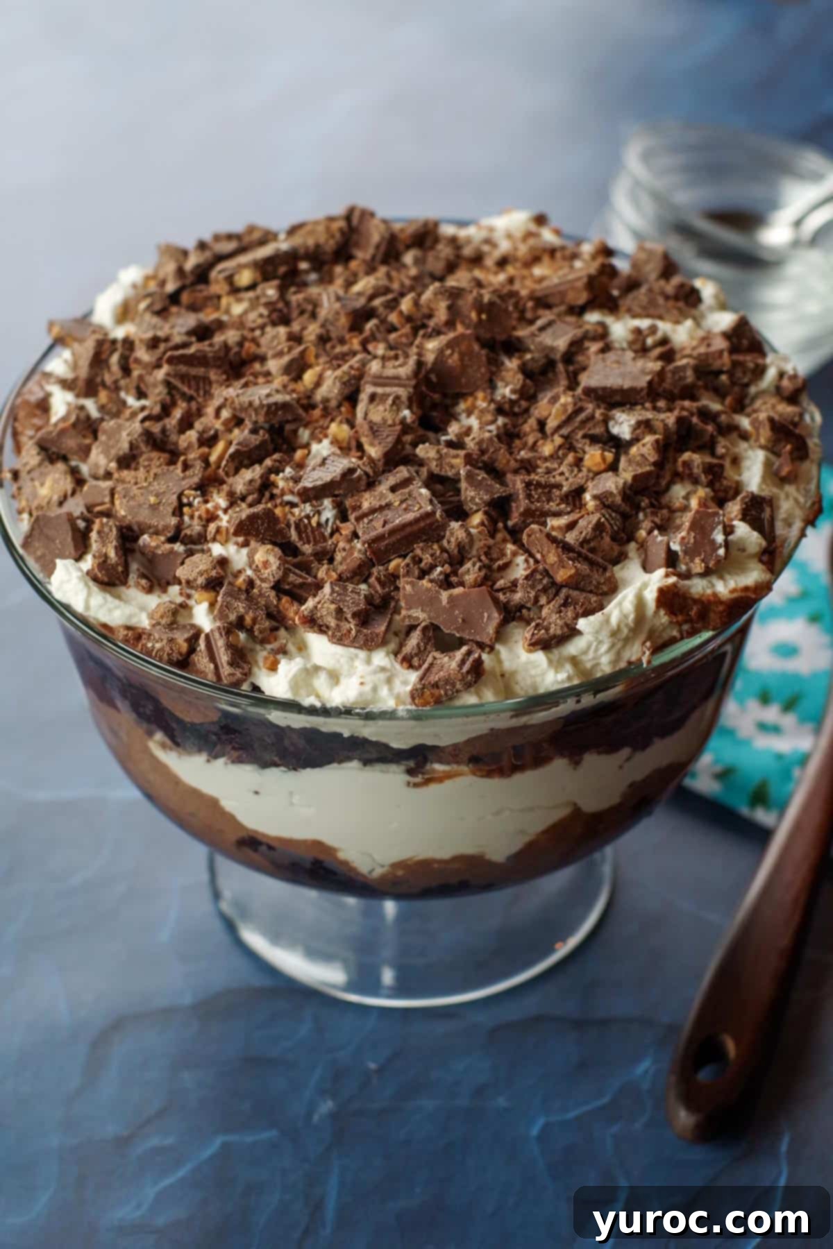 Kahlua-Spiked Death by Chocolate Trifle 15 death by chocolate trifle on a blue surface with small glass bowls in the background and a tea towel with a wooden spoon on the side