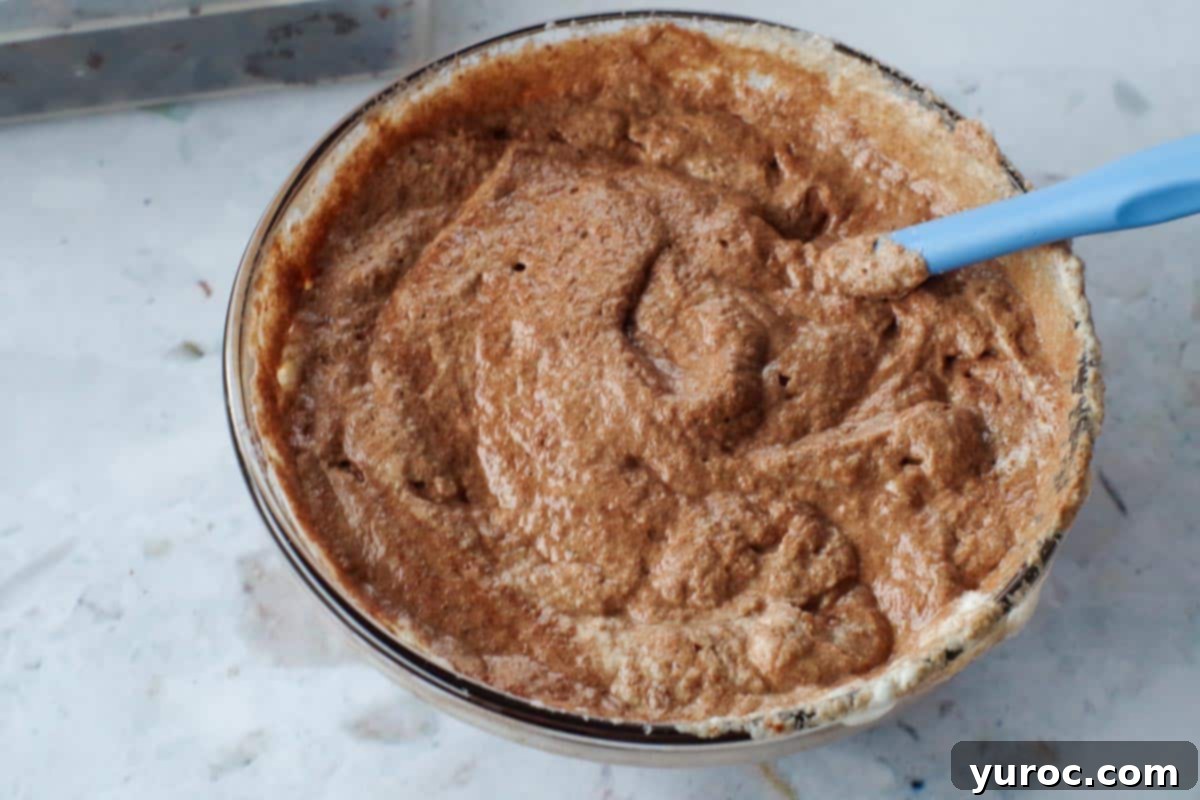 Kahlua-Spiked Death by Chocolate Trifle 8 egg whites mixed with chocolate mixture in glass bowl with blue spatula
