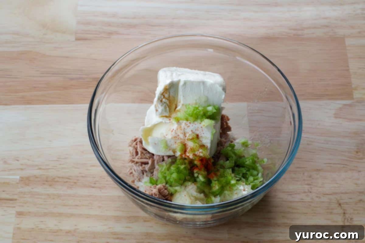 Creamy Tuna Dip 4 All tuna dip ingredients, including drained tuna, softened cream cheese, minced celery, minced onion, lemon juice, paprika, and Tabasco sauce, gathered in a large glass mixing bowl.