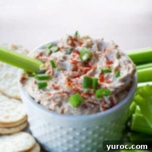 Creamy Tuna Dip 10 Creamy tuna dip in a white serving bowl with a celery stick, surrounded by crackers.