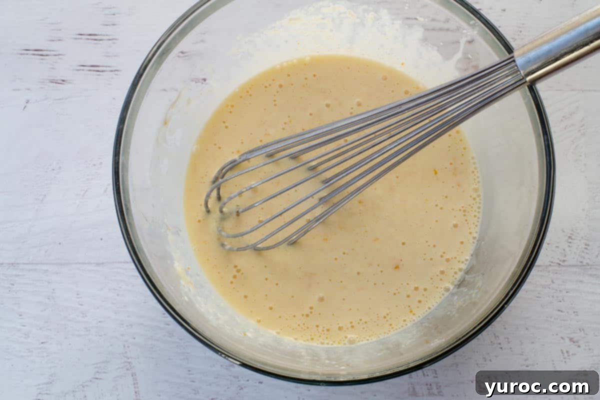 wet ingredients mixed together in large glass bowl, with whisk