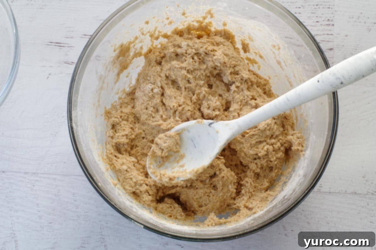 dry ingredients mixed with wet ingredients in large glass bowl with spoon