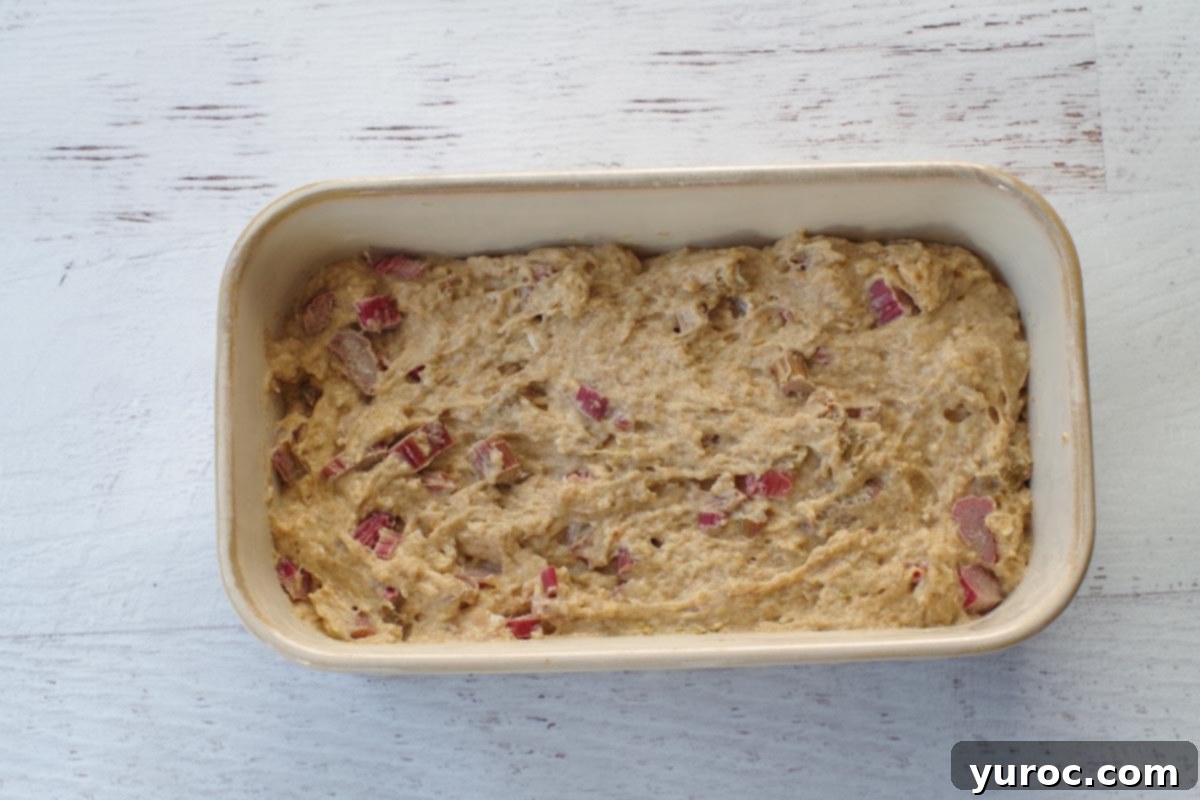 batter poured into prepared beige ceramic loaf pan