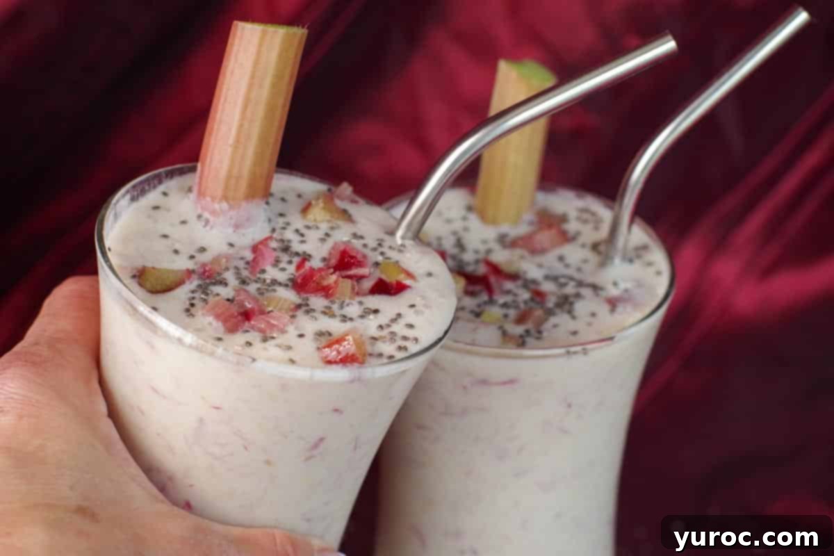 Two vibrant rhubarb smoothies clinking glasses in celebration