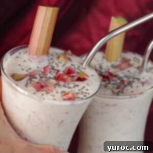 Two healthy rhubarb smoothies clinking glasses