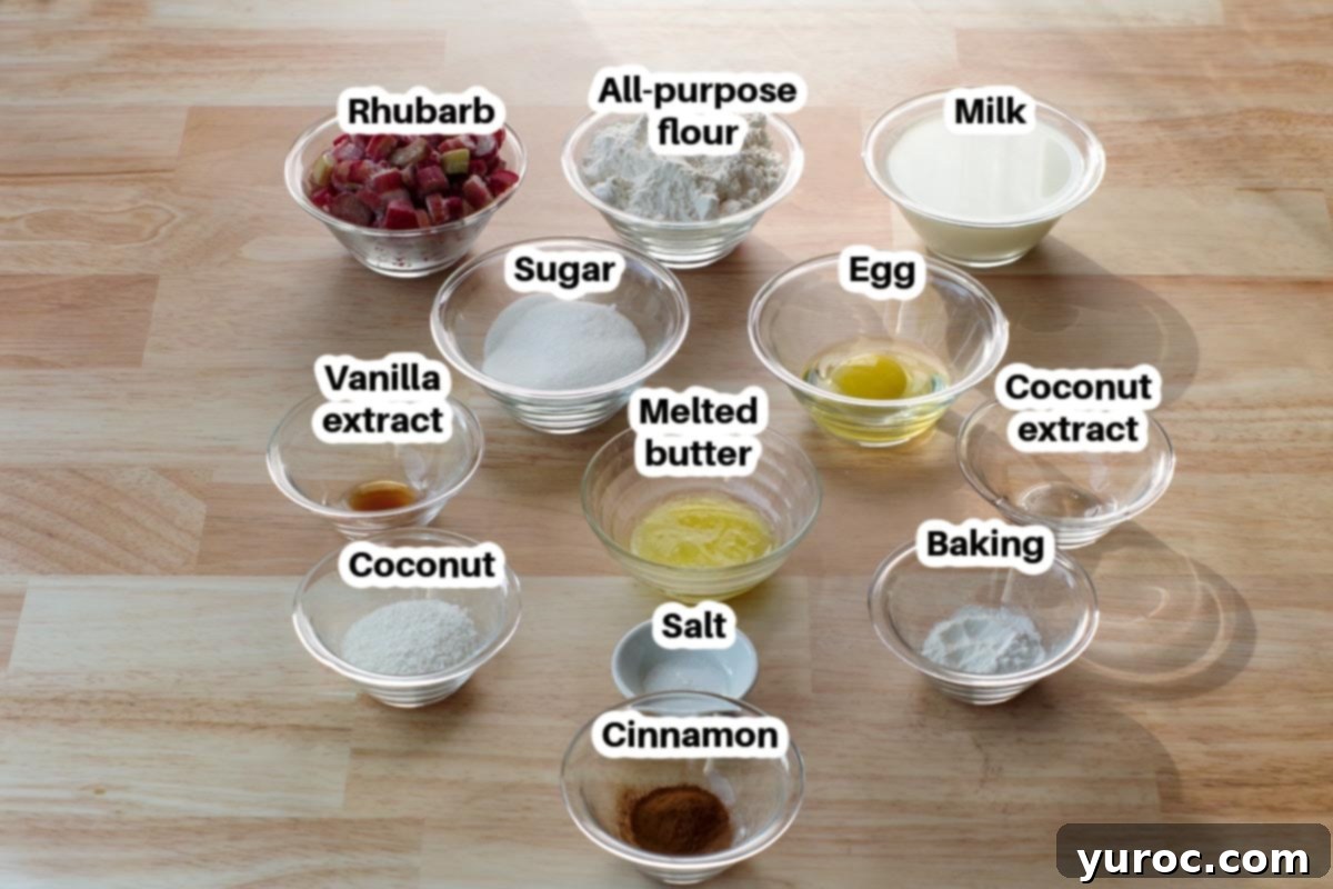 Various ingredients for rhubarb pancakes displayed in glass bowls, including flour, sugar, cinnamon, coconut flakes, baking powder, and salt, with a bowl of rhubarb in the center.