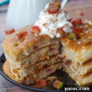 Four stacked rhubarb pancakes with a piece cut out, showcasing the delicious interior.