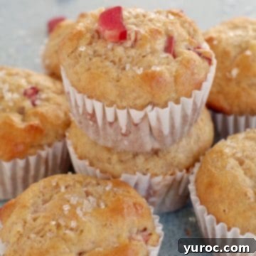 rhubarb muffin stacked on top of other rhubarb muffins with a piece of rhubarb on top