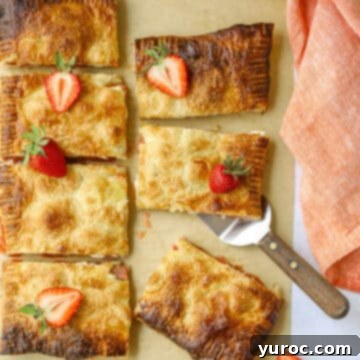 strawberry rhubarb puff pastry cut into pieces with strawberries on top of some pieces