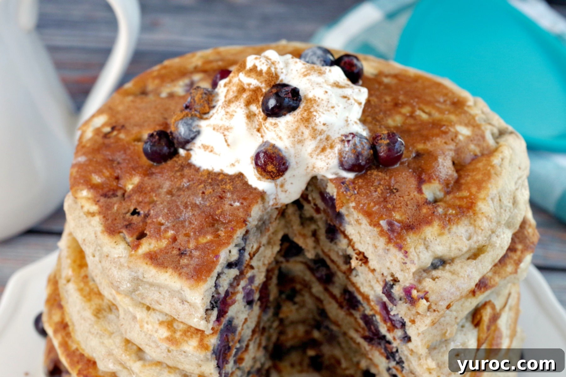 A top-down view of Saskatoon berry pancakes, featuring a cut-out portion from the middle of one pancake, highlighting the berries and texture.