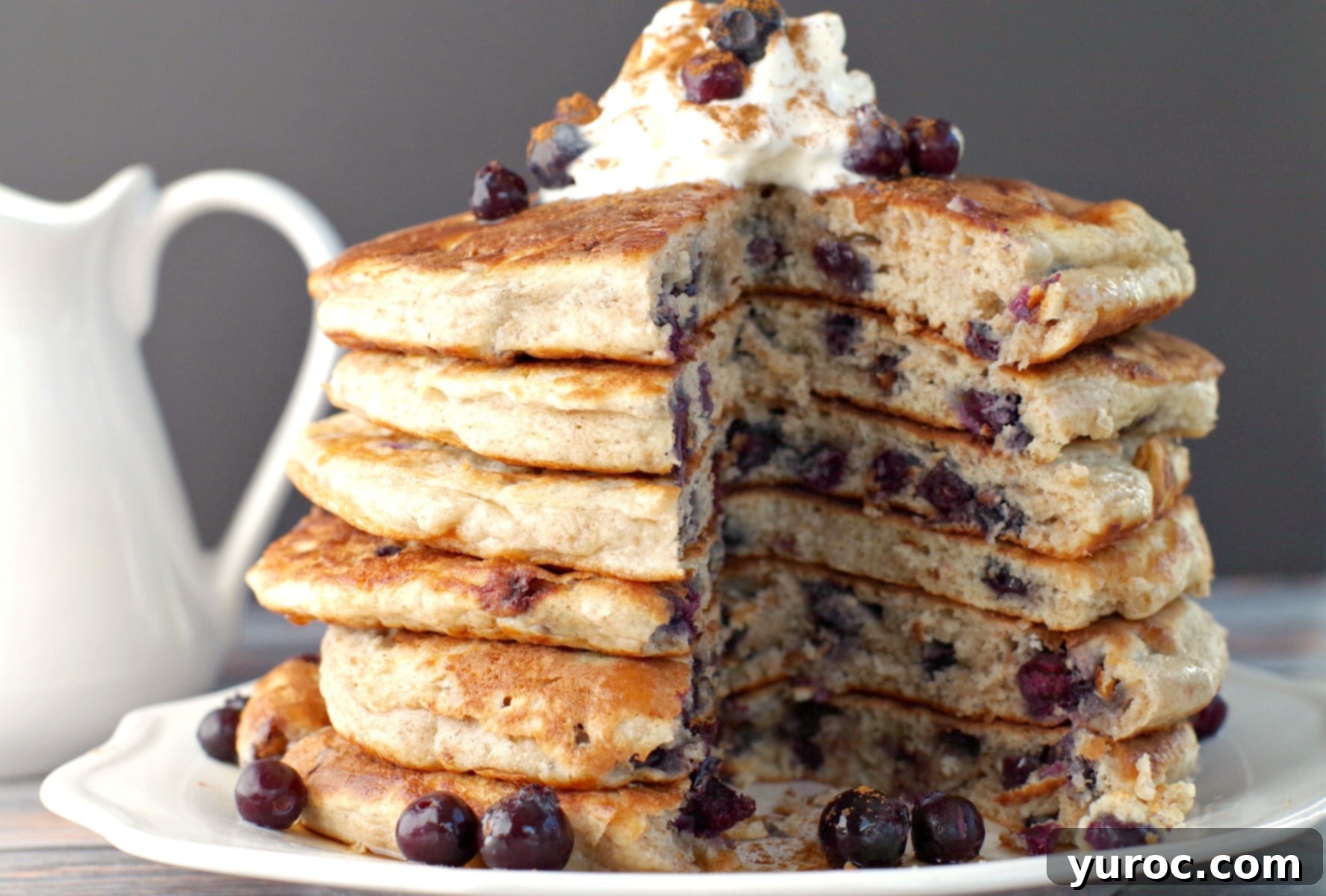 A stack of Saskatoon Berry Pancakes with one pancake cut out from the middle to show the fluffy interior and berries.