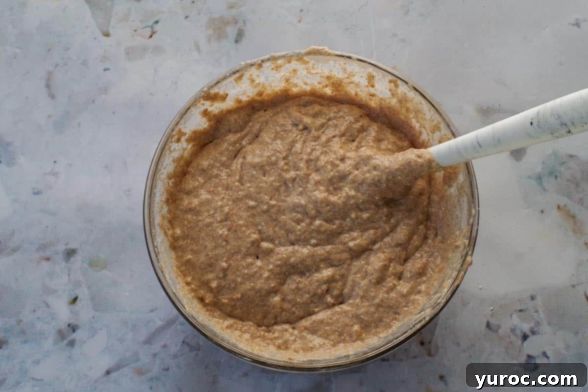 Wet ingredients being poured into the dry mixture in a medium-sized bowl, ready to be combined into batter.