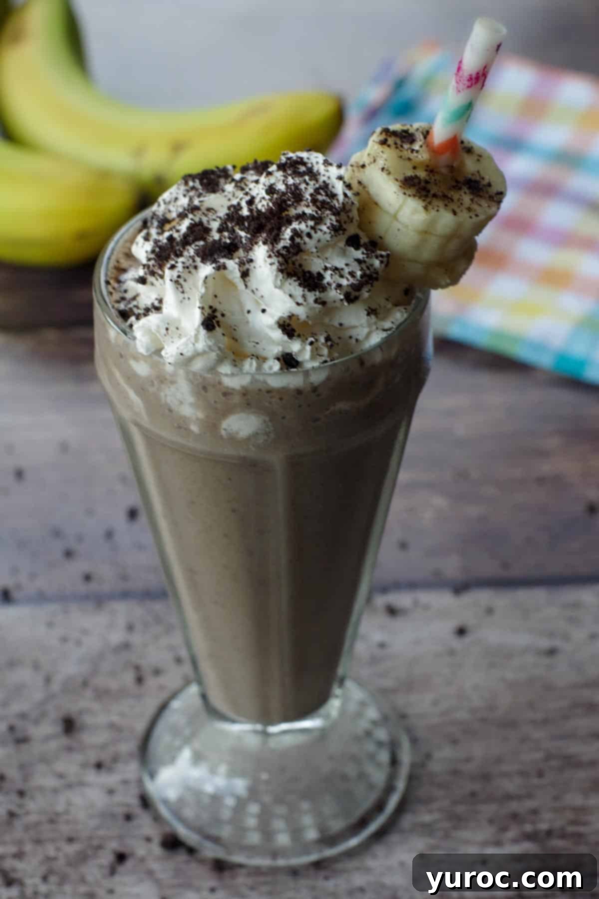 Guilt-Free Oreo Banana Milkshake 6 A perfectly blended Oreo banana milkshake, garnished with banana slices and a sprinkle of Oreo crumbs, with whole bananas visible in the background.