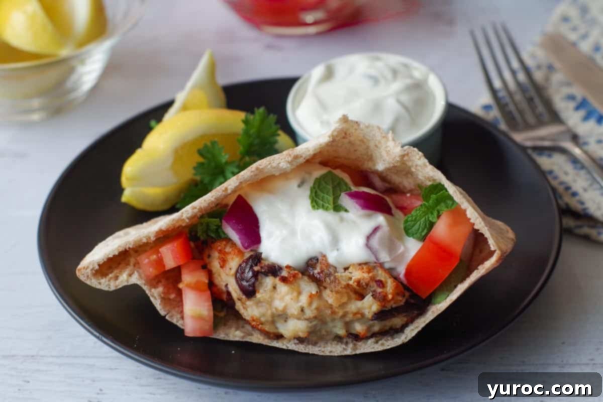 Guilt-Free Oreo Banana Milkshake 7 A Greek chicken burger in a soft pita, served on a black plate with a lemon wedge and a small dish of tzatziki sauce.