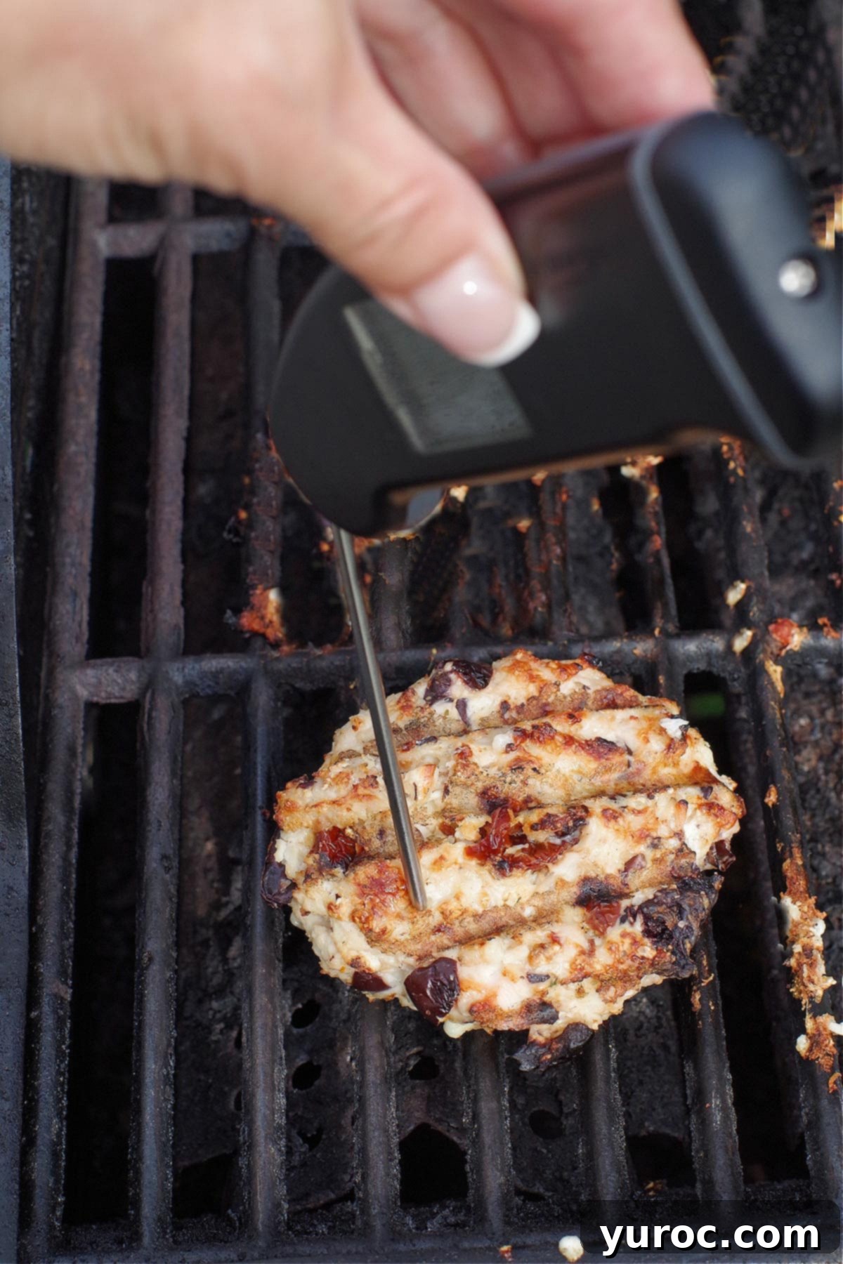 instant-read thermometer taking temperature of chicken burger on grill